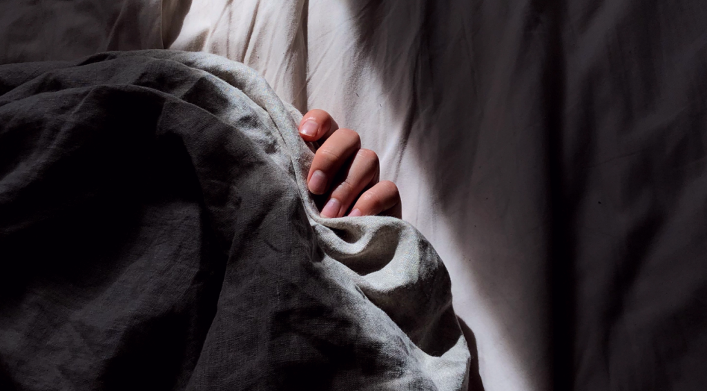 Pessoa deitada com preguiça segurando o cobertor
