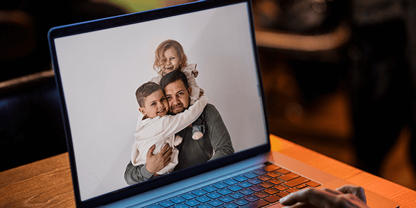 Foto do pai com seu filho e sua filha exibida no laptop.